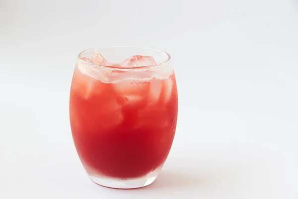 Um copo de saboroso suco de morango frio com gelo na mesa . — Fotografia de Stock