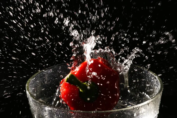 Splashing water from glass bowl with red pepper chili — Stock Photo, Image