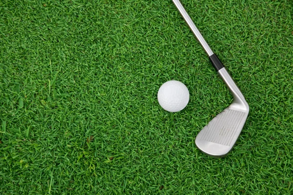 Iron golf club and ball on a green grass — стоковое фото