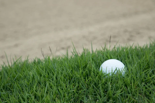 Μπάλα του γκολφ στη χλόη κοντά σε το οχυρό της άμμου — Φωτογραφία Αρχείου