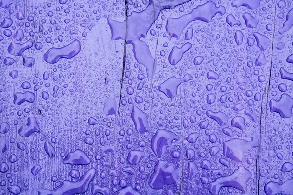 Regndroppar på violett trä — Stockfoto