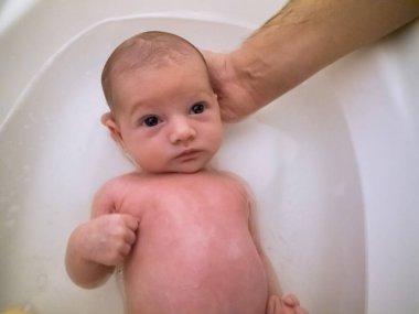 Küçük beyaz bir bebek. Oldukça rahat, banyo yapıyor.