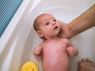 Küçük beyaz bir bebek. Oldukça rahat, banyo yapıyor.