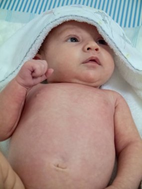 Küçük beyaz bir bebek. Banyo yaptıktan sonra havlusuyla oldukça rahat.