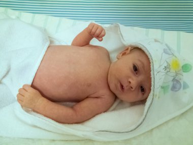 Küçük beyaz bir bebek. Banyo yaptıktan sonra havlusuyla oldukça rahat.