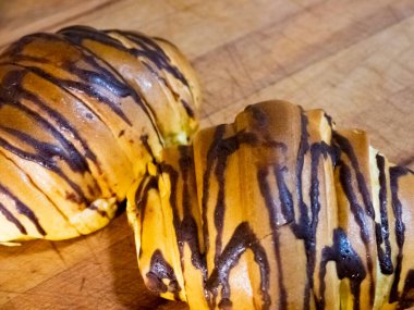 İki ay çöreğinin yakın görüntüsü. Çikolata sosu var ve ahşap bir masada dinleniyorlar..