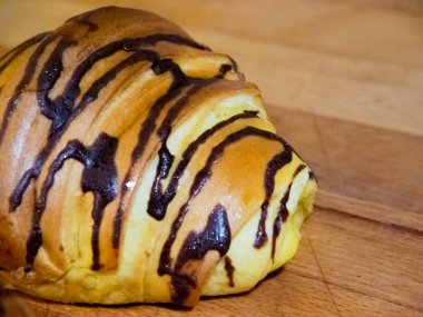 Ay çöreğinin yakın görüntüsü. Çikolata sosu var ve ahşap bir masada duruyor.