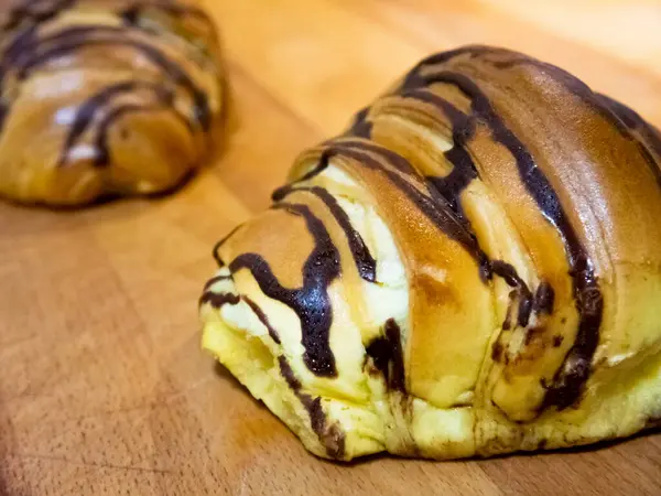 Close View Two Croissants Have Chocolate Topping Resting Wooden Table — Stock Photo, Image