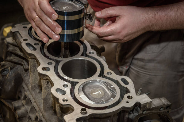 mechanic repairs the car engine in the workshop, install the piston