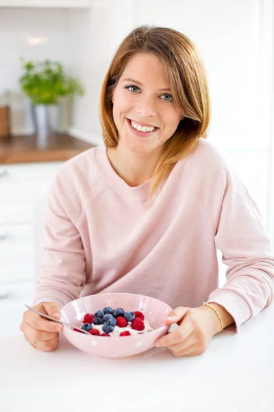 Jonge vrouw in haar huis keuken eten ontbijt — Stockfoto