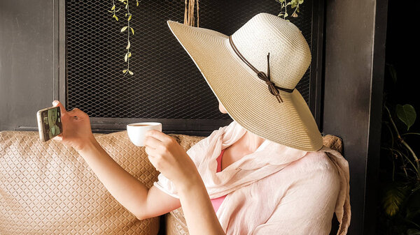 Female tourist with straw hat taking selfie 