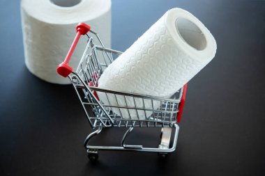 Oyuncak alışveriş arabasındaki tuvalet kağıdı, koronavirüs salgını nedeniyle depolama konsepti.