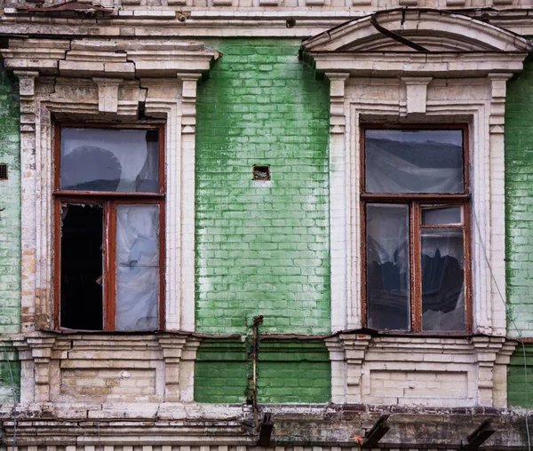 Δύο σπασμένα ξύλινα παράθυρα στην πρόσοψη πράσινο τούβλο από μια παλιά unkemp — Φωτογραφία Αρχείου