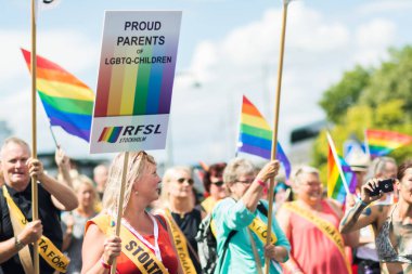 Stockholm gurur geçit töreni sırasında gökkuşağı bayrakları sallayarak mutlu kalabalıkta Lgbt çocuklar gururlu anne bir işaret tutan kadın