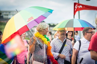 Gökkuşağı şemsiye tutan kalabalığın içinde Stockholm gurur geçit töreni sırasında insanlar