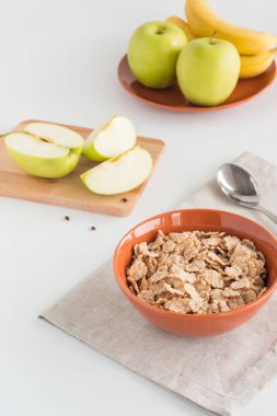 Taze elma kesilmiş parçalar, muz, beyaz arka plan üzerinde ahşap tahta kase mısır gevreği