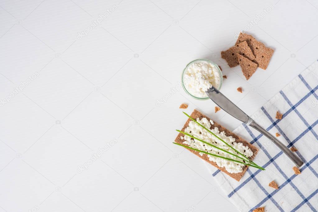 Brown rye crispy bread (Swedish crackers) with spread cottage cheese, decorated with thin green onion