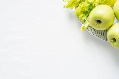 Taze yeşil elma ve beyaz bez zemin üzerine kereviz