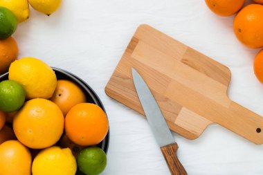 Tüm turuncu farklı türde bir kase: portakal, greyfurt, limon ve limon ve kopya alanı ile beyaz bez arka plan üzerinde kesim için hazır bir bıçakla boş ahşap tahta