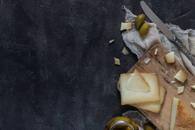 İtalyan sert peynir pecorino toscano dilimlenmiş ve bıçak ve yeşil zeytin ile ahşap tahta üzerinde doğranmış