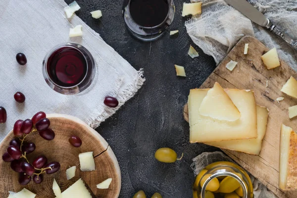 Peynir tabağı İspanyol sert peynir manchego doğranmış ve Cam Kavanoz, bıçak, kırmızı üzüm ve iki bardak kırmızı şarap yeşil zeytin ile ahşap kurullarında İtalyan pecorino toscano dilimlenmiş