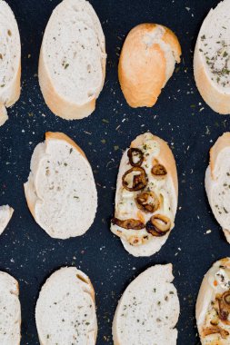 Brittany bölgesi veya siyah fırın tepsisinde, üstten görünüm bir desen oluşturan brie, karamelize soğan ve kuru otlar, Fransız peyniri baget dilimleri ile ev yapımı peynir dip yaptı