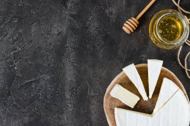 Bal ve rustik koyu arka plan kopya alanı, üstten görünüm ile kaşık ile ahşap kesim üzerinde brie peyniri dilimlenmiş