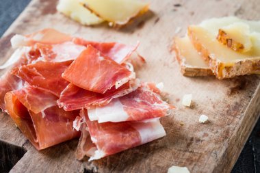İspanyolca jambon jamon serrano veya İtalyan prosciutto crudo ve dilimlenmiş İtalyan sert peynir pecorino toscano eski ahşap tahta üzerinde