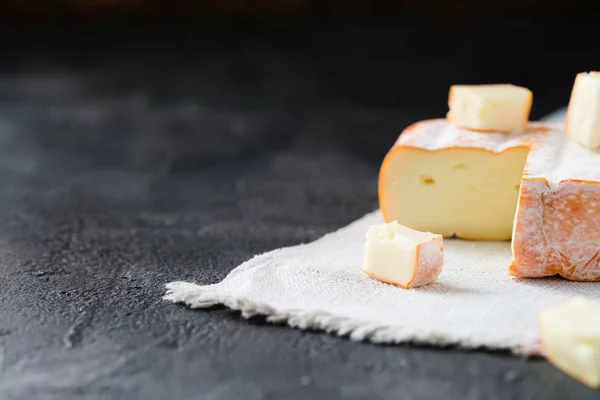 Γαλλικό μαλακό τυρί φέτες σε ύφασμα σε σκούρο φόντο για ρουστίκ περιοχή της Βρετάνης — Φωτογραφία Αρχείου