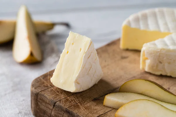 Closeup γαλλικό μαλακό τυρί από την περιοχή της Νορμανδίας φέτες με αχλάδι σε ένα ξύλινο ταμπλό σε λευκό φόντο — Φωτογραφία Αρχείου