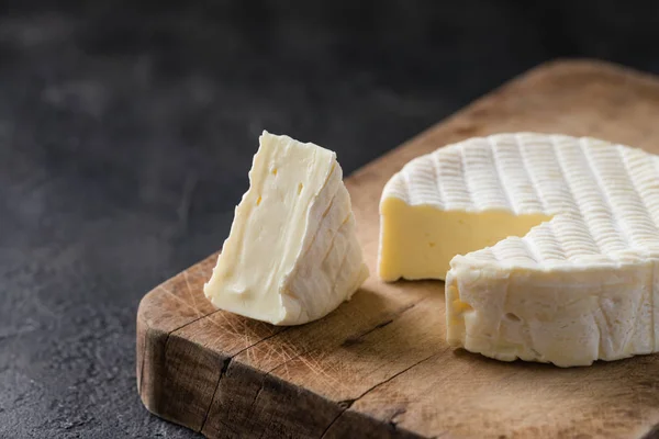 Γαλλικό μαλακό τυρί από Νορμανδία περιοχή με ένα κομμάτι σε ένα ξύλινο ταμπλό σε σκούρο φόντο για ρουστίκ — Φωτογραφία Αρχείου