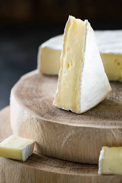 Closeup μαλακό τυρί brie φέτες σε ξύλινα περικοπές, σε σκούρο φόντο για ρουστίκ — Φωτογραφία Αρχείου