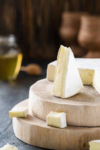 Μαλακό τυρί brie φέτες σε ξύλινα τεμάχια με μέλι σε σκούρο φόντο για ρουστίκ — Φωτογραφία Αρχείου