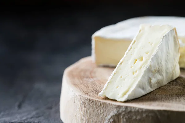 Closeup μαλακό τυρί brie φέτες σε ξύλινα κομμένα σε σκούρο φόντο για ρουστίκ — Φωτογραφία Αρχείου