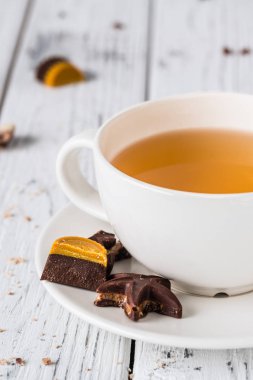 Fincan çay beyaz ahşap zemin üzerinde ham el yapımı çikolata şekerleme ile. Sağlıklı kahvaltı vegan tatlılar