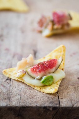 Pişmiş yumuşak çiplerle brie incir, Antep fıstığı ve bal ile peynir. Ahşap tahta üzerinde snack kavramı. Seçici odak