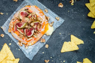 Doğranmış incir, ceviz ve bal koyu arka plan üzerinde eritilmiş pişmiş Fransızca yumuşak peynir Brittany bölgesinden kaplı. Aperatif kavramı fiş ile. Üstten Görünüm