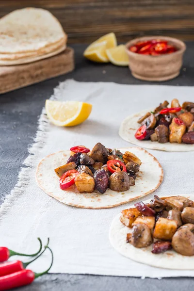 Tacos with grilled mushrooms, Spanish spicy sausage chorizo, Mexican tortillas, Cypriot cheese halloumi, hot chilly, dried oregano, slices of lime and lemon, on cloth — Stock Photo, Image