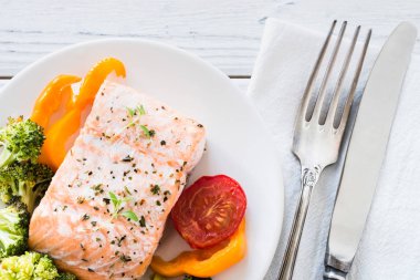 Tabakta sebze ile pişmiş somon. Beyaz ahşap masa