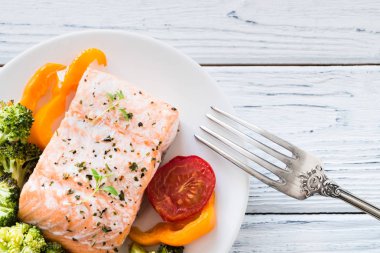 Tabakta sebze ile pişmiş somon. Beyaz ahşap masa