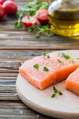 Çiğ çiğ somon ve sebzeler üzerinde ahşap masa 