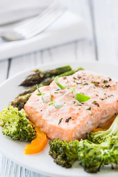 Gebackener Lachs mit Gemüse auf Teller. weißer Holztisch — Stockfoto