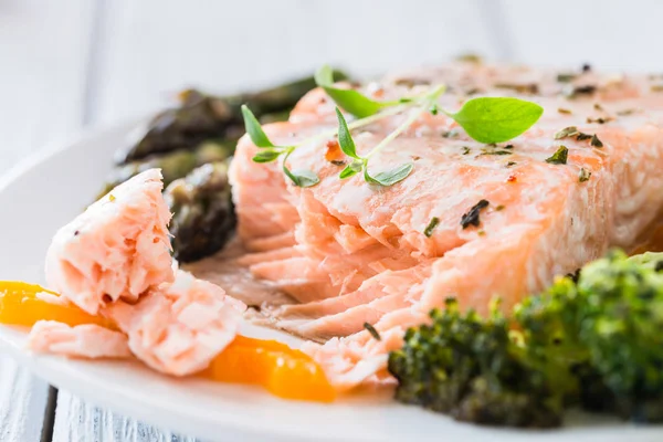 Gebackener Lachs mit Gemüse auf Teller. weißer Holztisch — Stockfoto