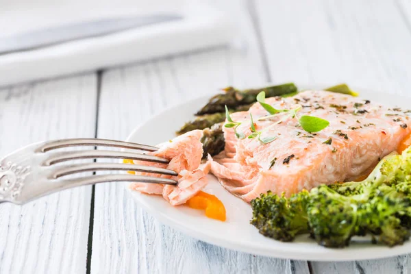 Gebackener Lachs mit Gemüse auf Teller. weißer Holztisch — Stockfoto