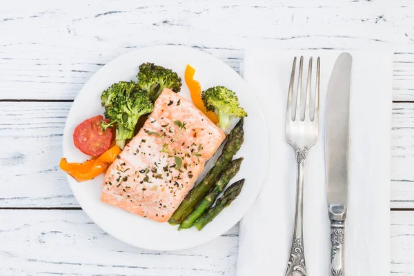 Gebackener Lachs mit Gemüse auf Teller. weißer Holztisch — Stockfoto