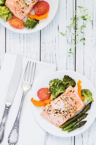 Gebackener Lachs mit Gemüse auf Teller. weißer Holztisch — Stockfoto