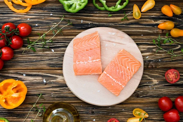 Rohes Gemüse auf Holztisch und Lachs auf Schneidebrett — Stockfoto