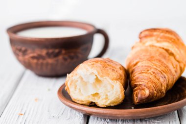 Kruvasan ve süt kahvaltı. Beyaz rustik masa