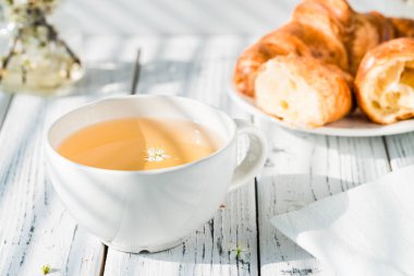 Bardak bitkisel çay ve taze kruvasanlar plaka üzerinde