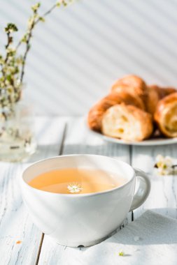 Bardak bitkisel çay ve taze kruvasanlar plaka üzerinde